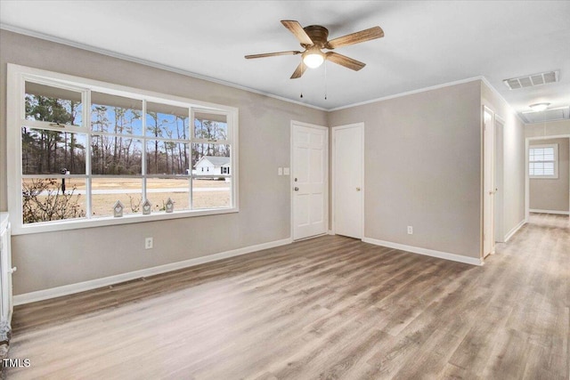 empty room featuring attic access, visible vents, wood finished floors, and ornamental molding