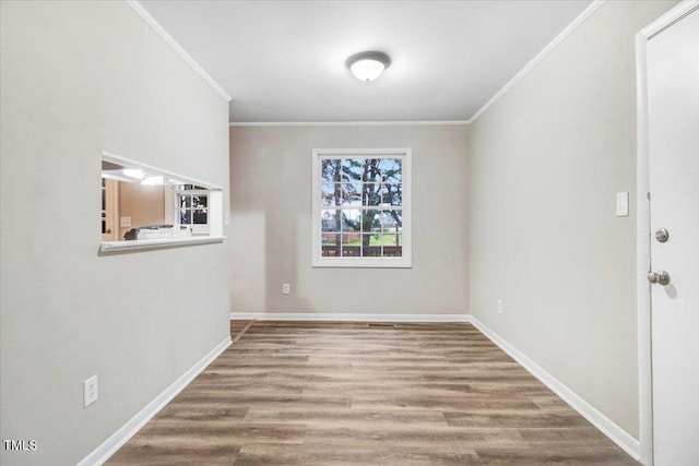 unfurnished room featuring crown molding, baseboards, and wood finished floors