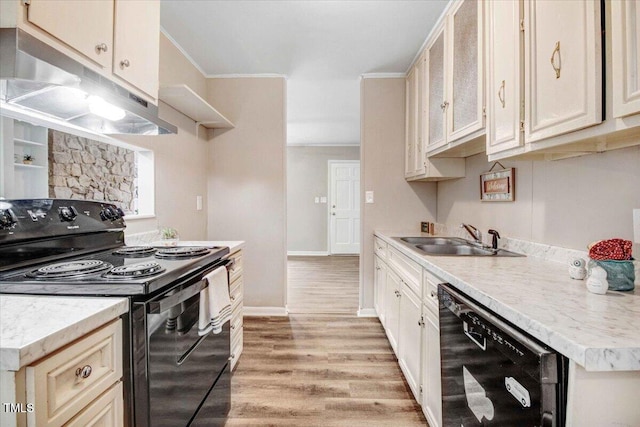 kitchen featuring light wood finished floors, light countertops, a sink, under cabinet range hood, and black appliances