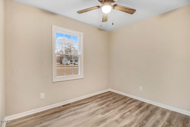 spare room featuring wood finished floors, visible vents, and baseboards