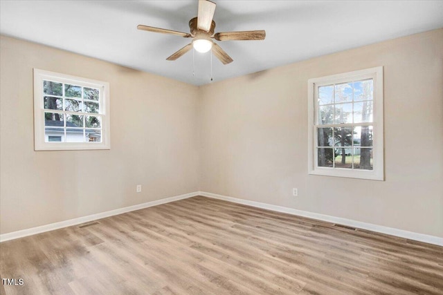 empty room with a ceiling fan, visible vents, baseboards, and wood finished floors