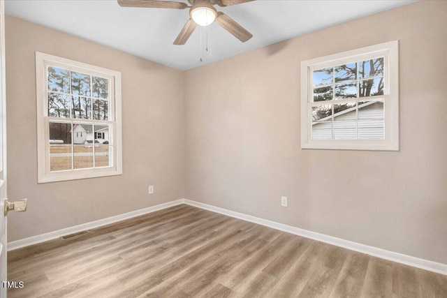 spare room featuring visible vents, ceiling fan, baseboards, and wood finished floors