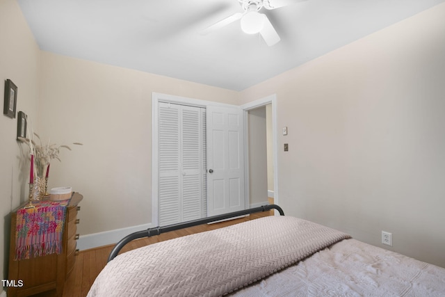 bedroom featuring a closet, wood finished floors, a ceiling fan, and baseboards