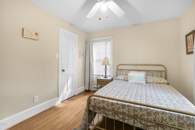 bedroom featuring a baseboard heating unit, ceiling fan, baseboards, and wood finished floors