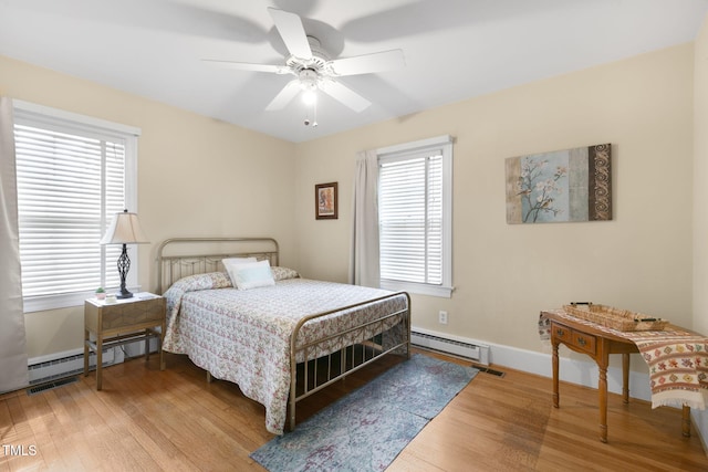 bedroom with a baseboard radiator, baseboards, baseboard heating, and wood finished floors