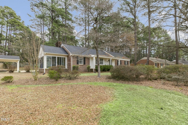 ranch-style house featuring brick siding, a chimney, and a front yard