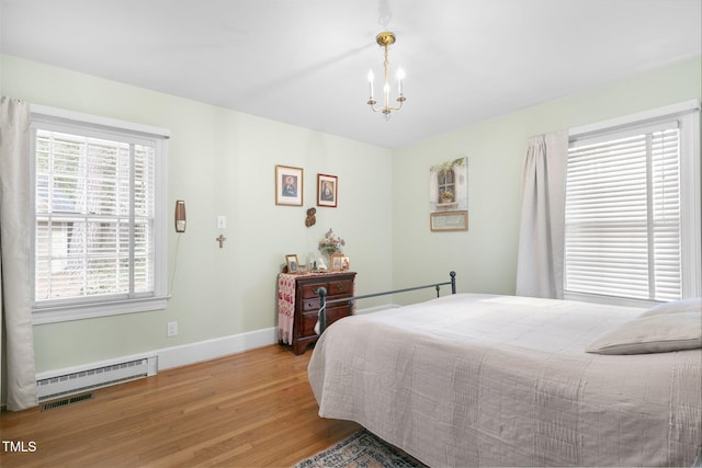 bedroom with a chandelier, a baseboard heating unit, visible vents, baseboards, and light wood finished floors