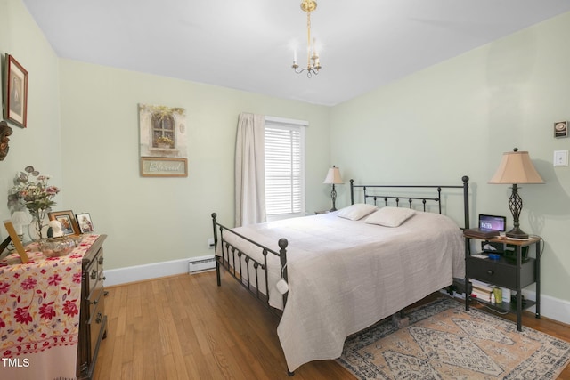 bedroom with light wood-style floors, baseboards, baseboard heating, and a chandelier