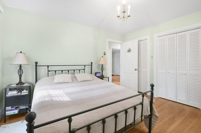 bedroom featuring a notable chandelier, light wood-style flooring, and multiple closets