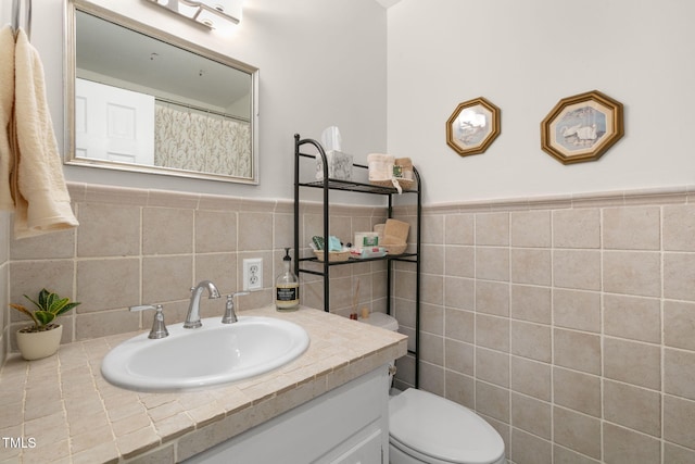 bathroom featuring tile walls, wainscoting, vanity, and toilet