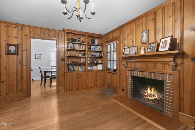 living room featuring ornamental molding, a brick fireplace, wood walls, and light wood-style flooring