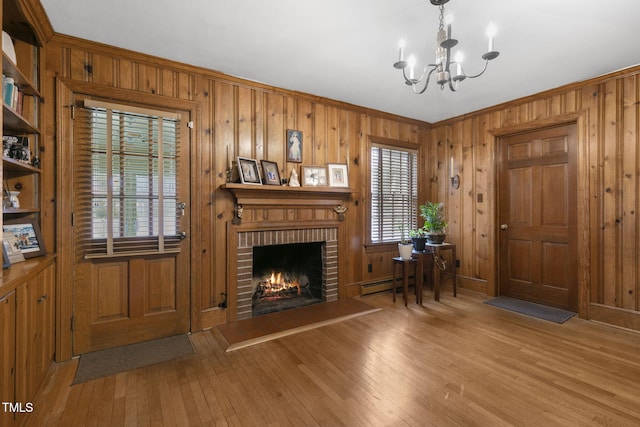 living area with a fireplace, a baseboard radiator, wooden walls, a chandelier, and hardwood / wood-style floors