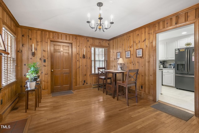 dining room featuring light wood-style floors, a baseboard radiator, ornamental molding, and an inviting chandelier