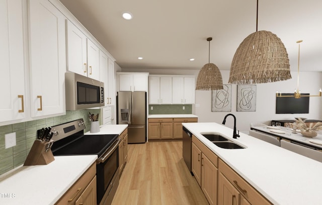 kitchen with stainless steel appliances, hanging light fixtures, white cabinets, a sink, and light wood-type flooring