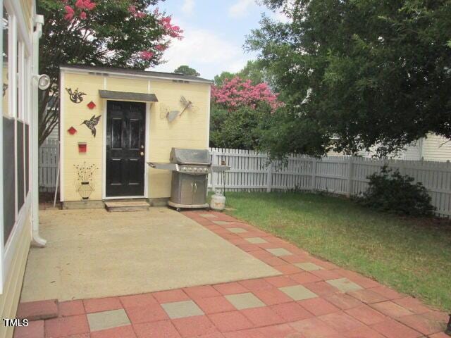 view of patio / terrace featuring an outbuilding, area for grilling, and fence