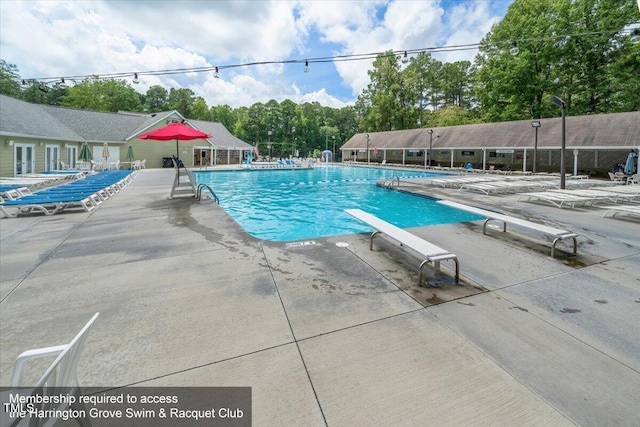 pool with fence, a patio area, and a diving board