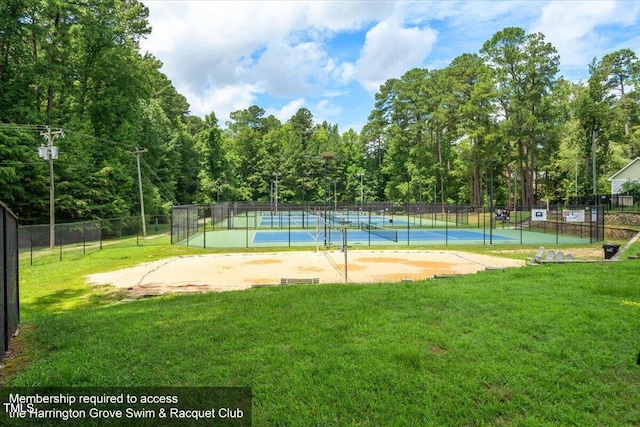 view of tennis court with a yard and fence