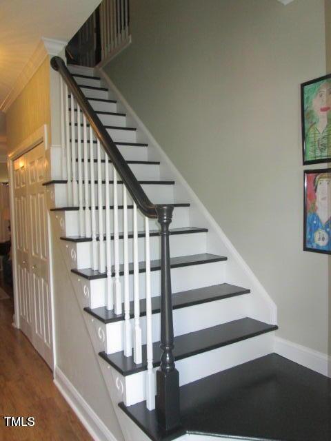 stairway featuring crown molding, baseboards, and wood finished floors