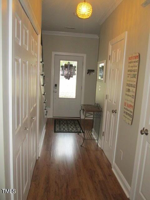 doorway with baseboards, wood finished floors, and ornamental molding