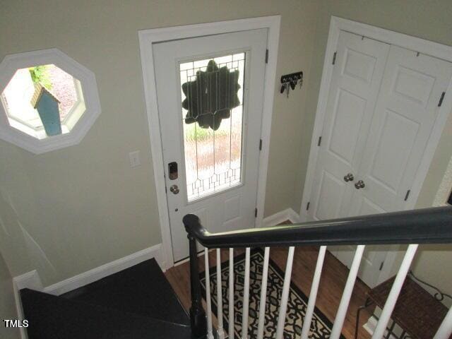 foyer entrance with dark wood-style floors, stairs, and baseboards