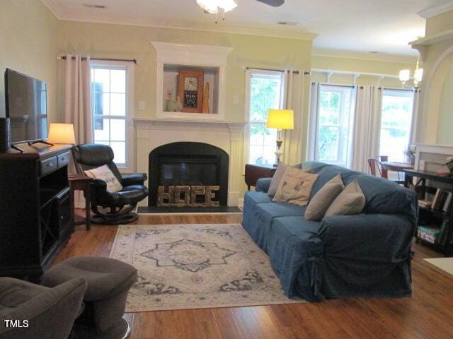 living area with wood finished floors, plenty of natural light, and a fireplace with raised hearth