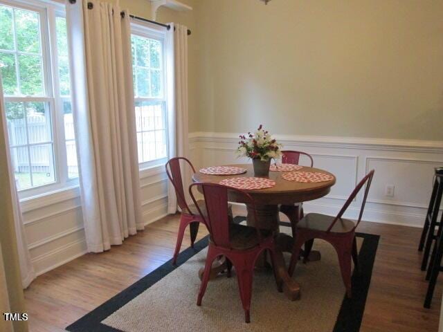 dining room with wainscoting, a decorative wall, and light wood-style flooring