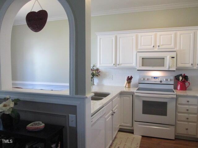 kitchen featuring crown molding, dark wood finished floors, light countertops, white cabinets, and white appliances