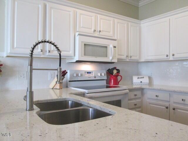 kitchen featuring tasteful backsplash, white appliances, white cabinetry, and light stone counters