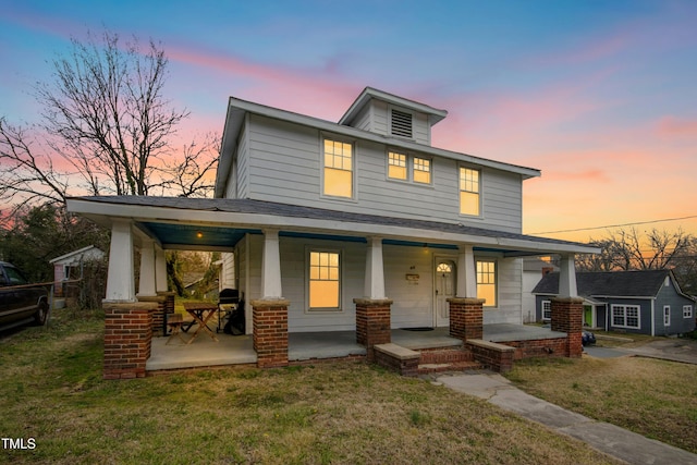 american foursquare style home featuring covered porch and a front yard