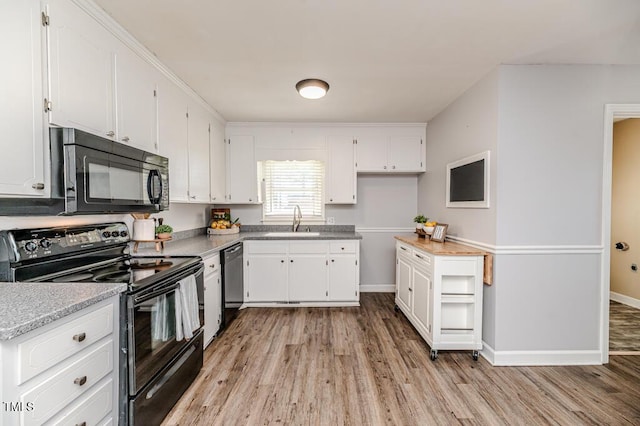 kitchen with white cabinets, black appliances, and a sink