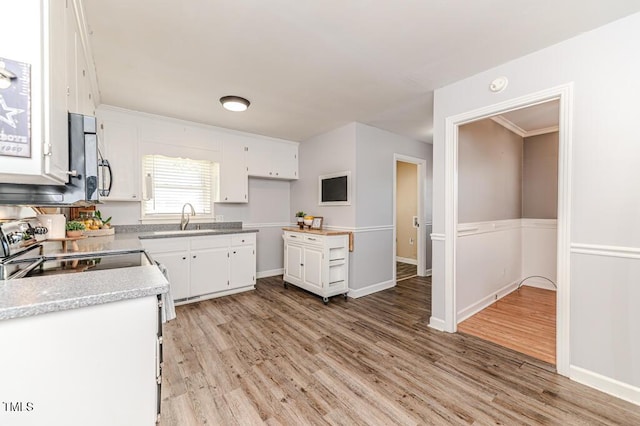 kitchen featuring light wood finished floors, range with electric stovetop, and white cabinetry