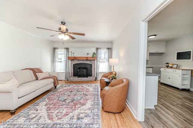 living room featuring ornamental molding, baseboards, ceiling fan, and wood finished floors