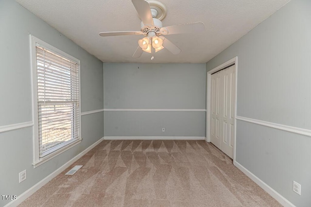 unfurnished room with baseboards, a textured ceiling, ceiling fan, and carpet floors