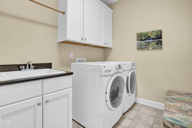 laundry room with baseboards, light tile patterned floors, cabinet space, independent washer and dryer, and a sink