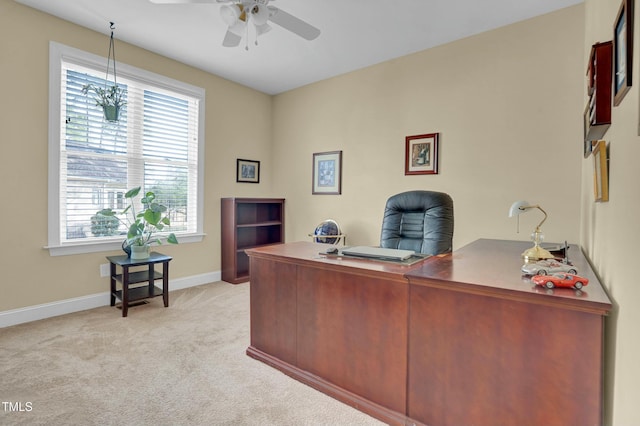 office space with a ceiling fan, light colored carpet, and baseboards