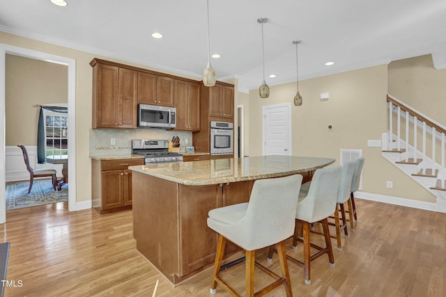 kitchen featuring a kitchen island, light wood-style flooring, ornamental molding, stainless steel appliances, and tasteful backsplash