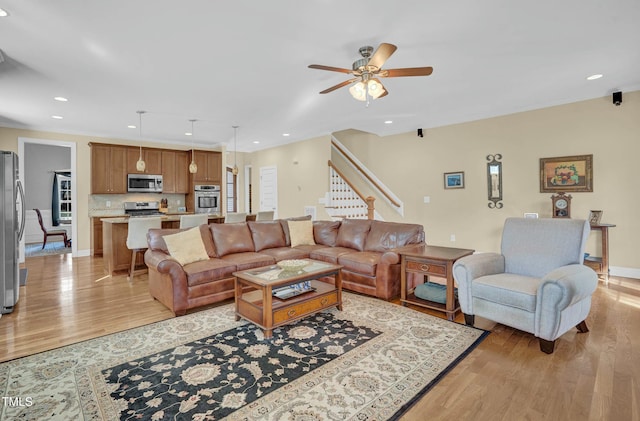 living area featuring baseboards, recessed lighting, ornamental molding, stairs, and light wood-type flooring