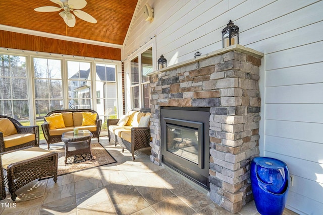 sunroom featuring ceiling fan, wooden ceiling, an outdoor stone fireplace, and lofted ceiling