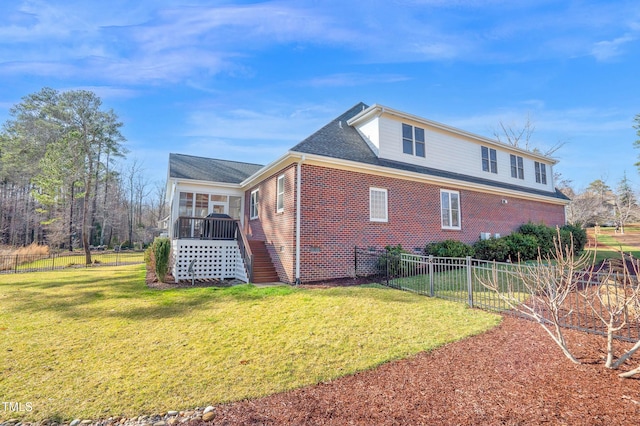 view of property exterior featuring brick siding, a lawn, fence, and a sunroom