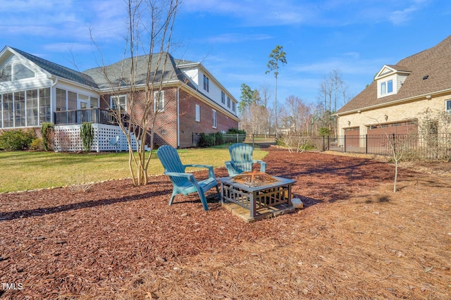 view of yard featuring a fire pit, fence, and a sunroom