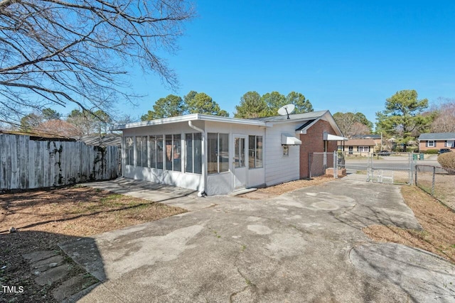 rear view of property with a sunroom, a gate, fence, and driveway