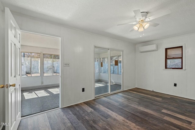 empty room with ceiling fan, a wall mounted AC, wood finished floors, and a textured ceiling