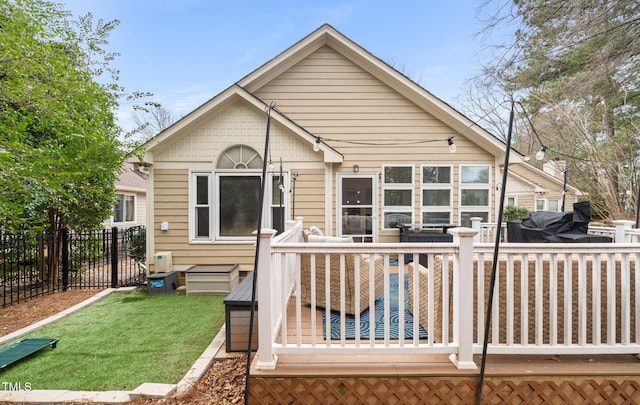 rear view of property with fence, a lawn, and a wooden deck