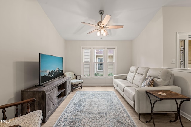 living room featuring baseboards, light wood-type flooring, and ceiling fan