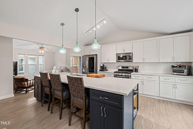 kitchen with a toaster, vaulted ceiling, white cabinets, stainless steel appliances, and a sink