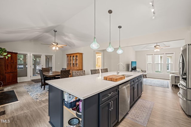 kitchen with lofted ceiling, a sink, stainless steel appliances, light countertops, and open floor plan