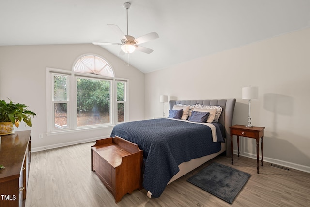 bedroom featuring light wood finished floors, visible vents, baseboards, vaulted ceiling, and a ceiling fan