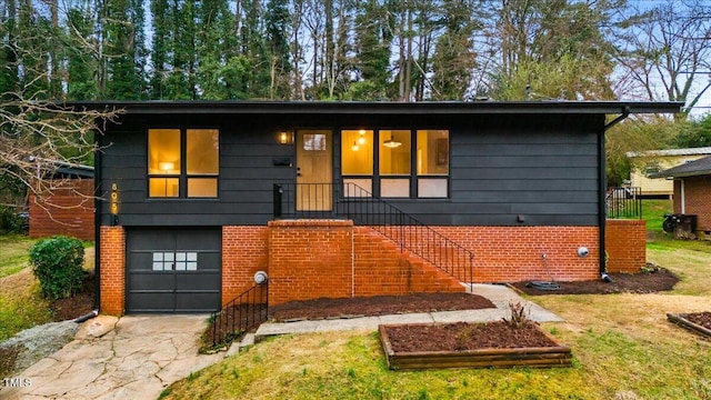 view of front of house with a garage, a front yard, concrete driveway, and brick siding