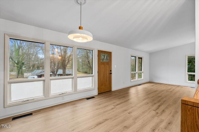 unfurnished living room featuring visible vents, vaulted ceiling, and light wood finished floors