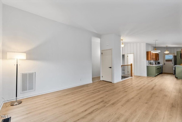 unfurnished living room featuring light wood-style flooring, visible vents, and baseboards